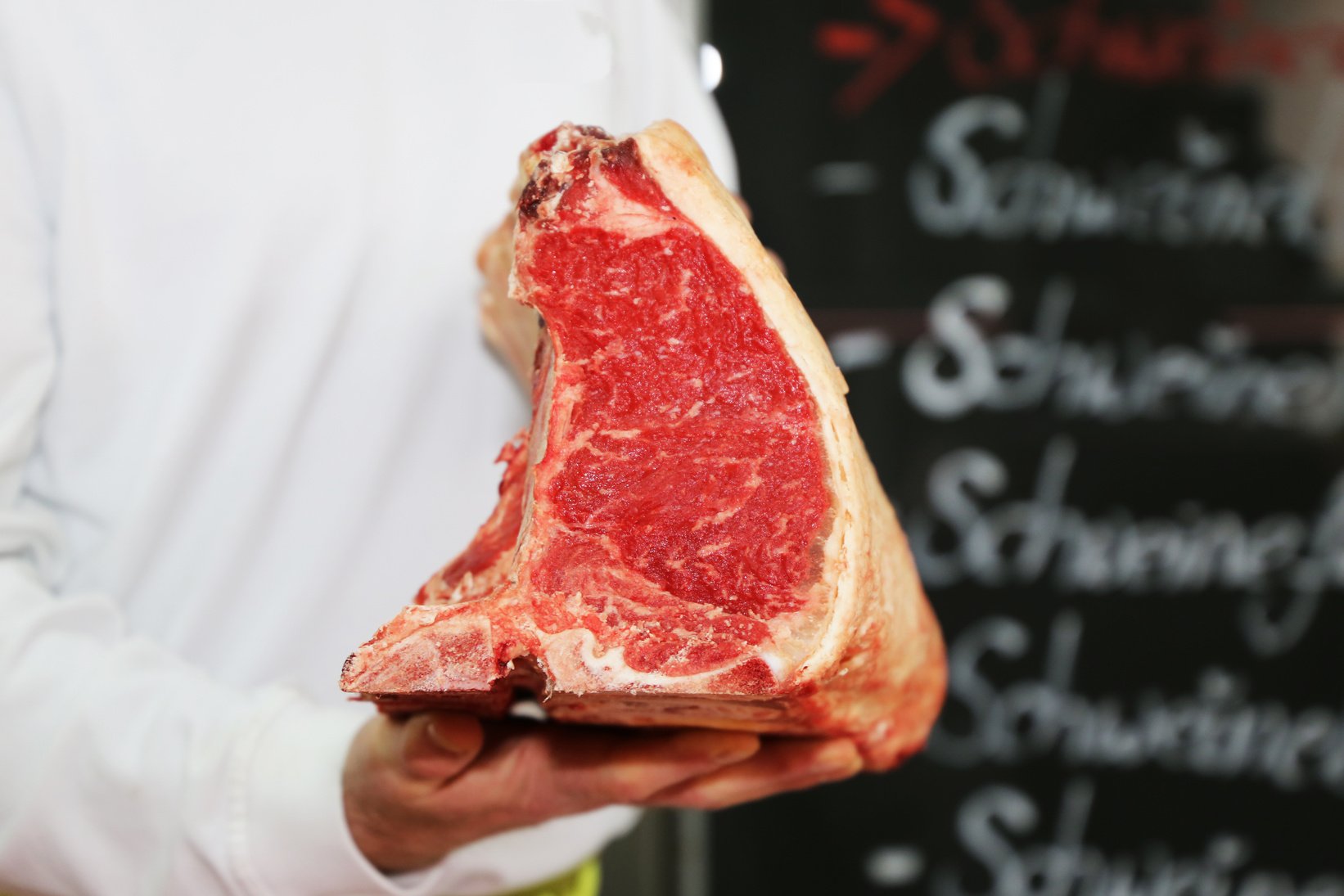 Butcher holds Dry Aged T-Bone Steak in hand