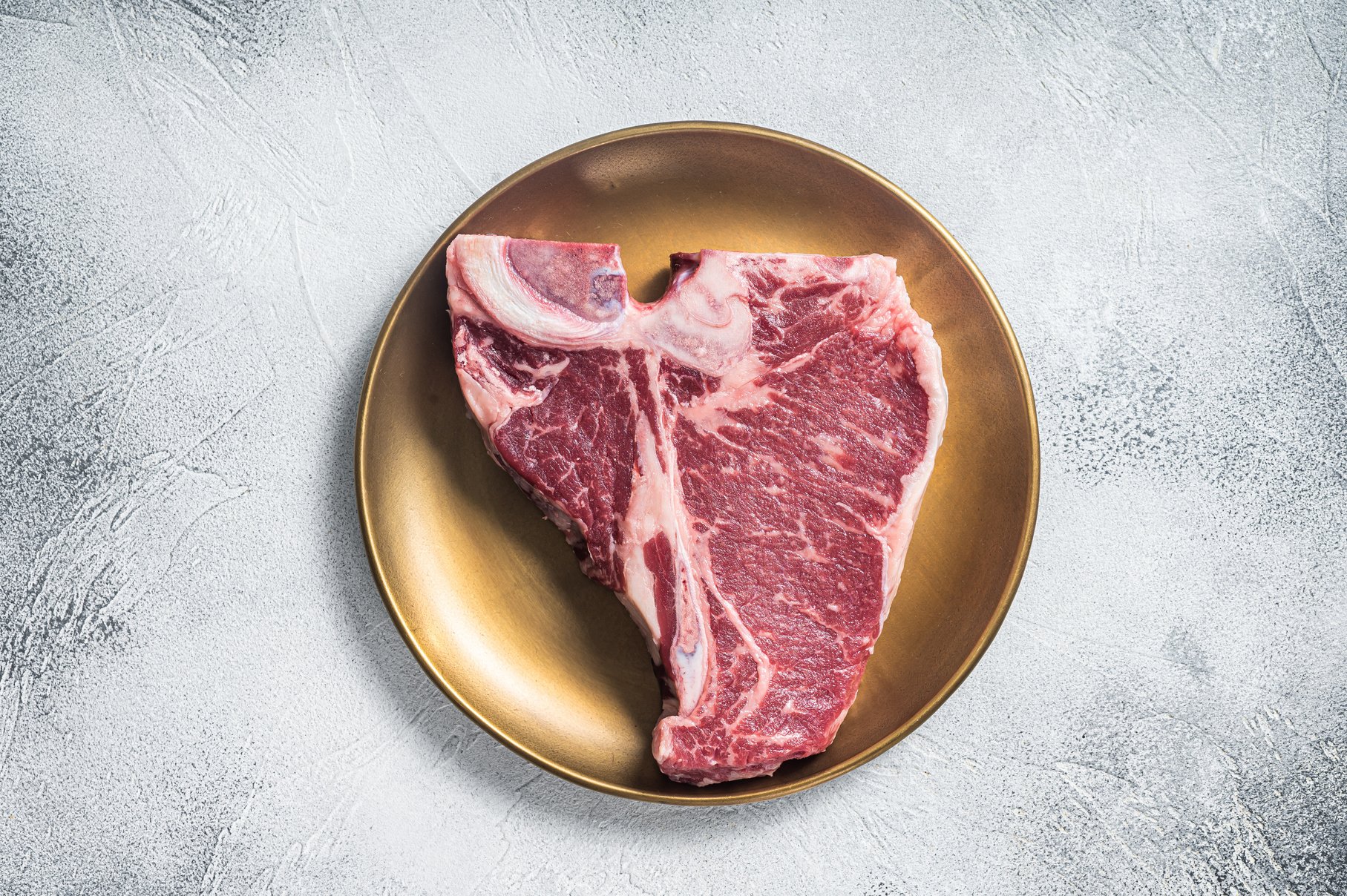 Raw T-bone porterhouse beef meat Steak on golden metalic pla